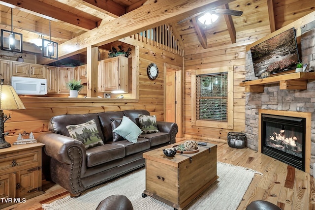 living room with light hardwood / wood-style flooring, wooden walls, lofted ceiling with beams, and a fireplace