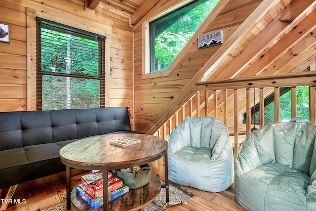 living room with vaulted ceiling, wooden walls, plenty of natural light, and hardwood / wood-style floors