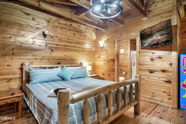 bedroom with wooden walls, beam ceiling, and hardwood / wood-style floors