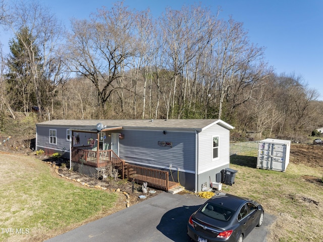 manufactured / mobile home featuring a deck, a front lawn, and aphalt driveway