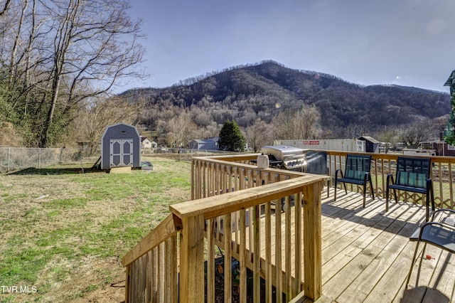 deck featuring an outbuilding, a storage unit, grilling area, a mountain view, and fence