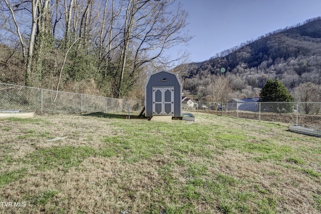 view of yard with an outbuilding, a storage shed, a mountain view, a wooded view, and a fenced backyard