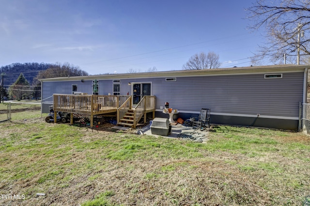 back of house with fence, a lawn, and a wooden deck