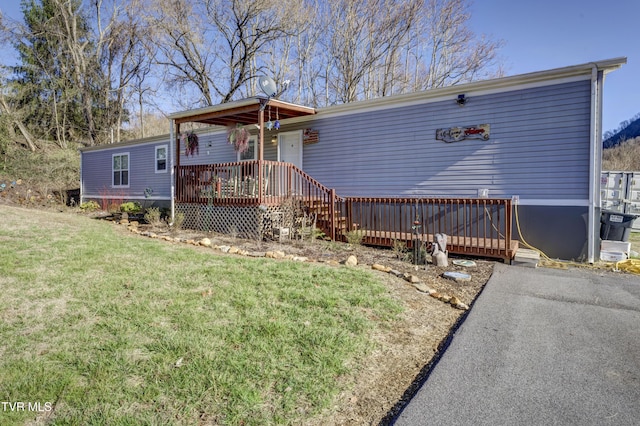 manufactured / mobile home with a wooden deck and a front lawn