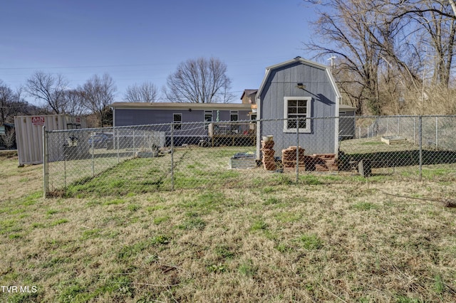 rear view of house with a yard, a storage unit, a gambrel roof, fence, and an outdoor structure