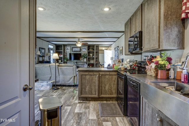 kitchen featuring wood finished floors, a peninsula, a textured ceiling, black appliances, and stainless steel counters