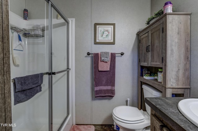 bathroom featuring toilet, a shower stall, and vanity