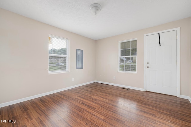 unfurnished room featuring electric panel, dark hardwood / wood-style flooring, and a textured ceiling