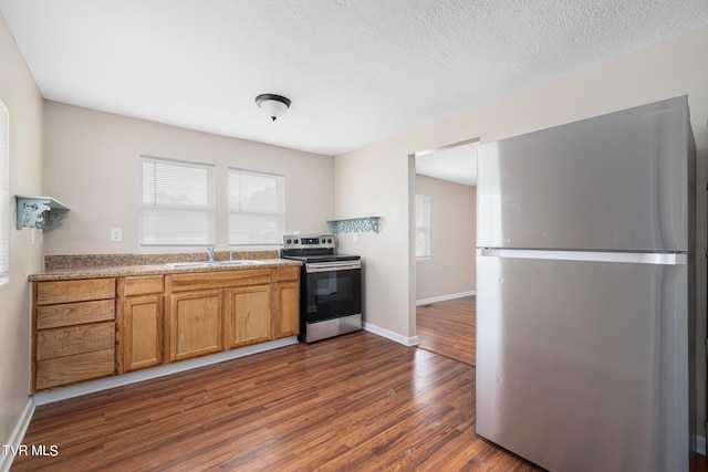 kitchen with a textured ceiling, sink, dark wood-type flooring, and stainless steel appliances