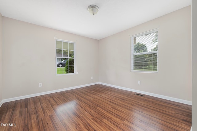 unfurnished room featuring a healthy amount of sunlight and dark hardwood / wood-style floors