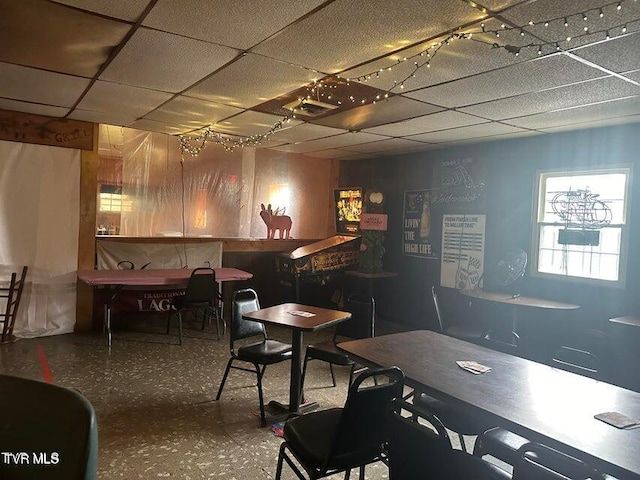 interior space featuring a drop ceiling, wooden walls, and bar