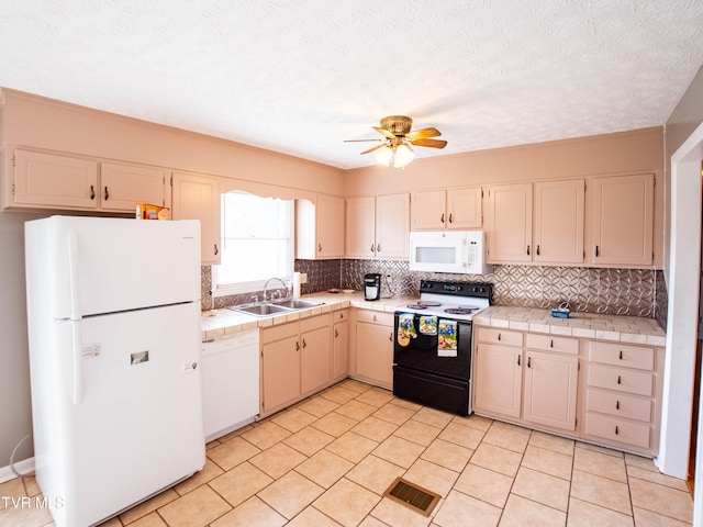 kitchen featuring ceiling fan, sink, white appliances, a textured ceiling, and tile counters