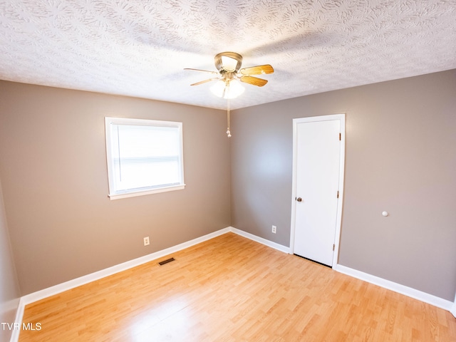 empty room with a textured ceiling, ceiling fan, and light hardwood / wood-style flooring