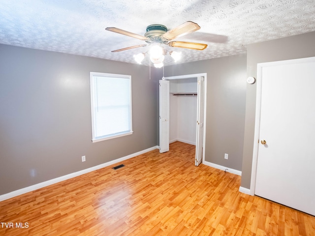 unfurnished bedroom featuring ceiling fan, a textured ceiling, light hardwood / wood-style flooring, and a closet