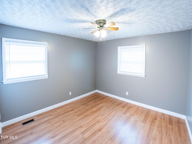 unfurnished room with a textured ceiling and light hardwood / wood-style floors