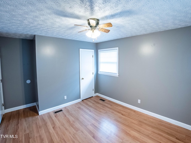 spare room with light hardwood / wood-style flooring, ceiling fan, and a textured ceiling