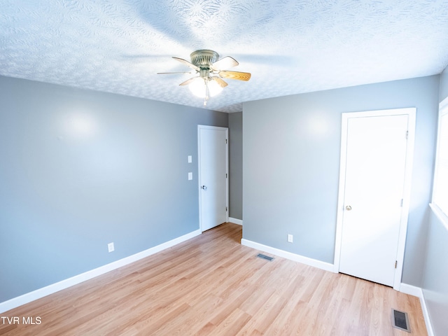 empty room with ceiling fan, a textured ceiling, and light hardwood / wood-style floors