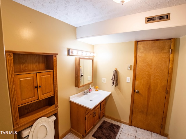 bathroom featuring a textured ceiling, vanity, toilet, and tile patterned floors