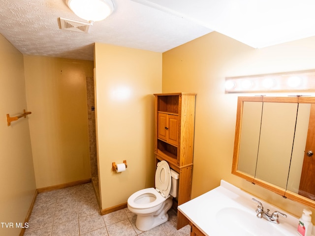 bathroom with vanity, tile patterned flooring, toilet, and a textured ceiling