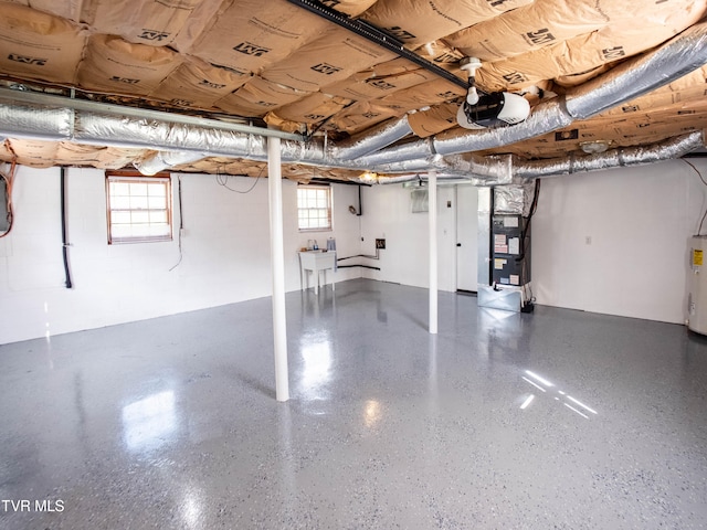 basement featuring heating unit, water heater, a healthy amount of sunlight, and sink