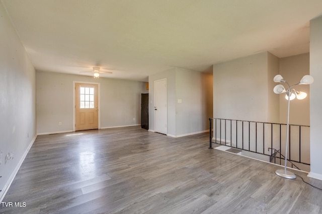 spare room with wood-type flooring and ceiling fan with notable chandelier