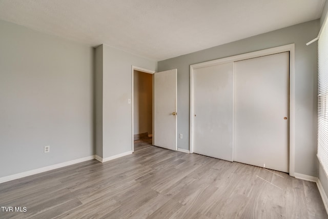 unfurnished bedroom featuring a closet, light hardwood / wood-style floors, and a textured ceiling