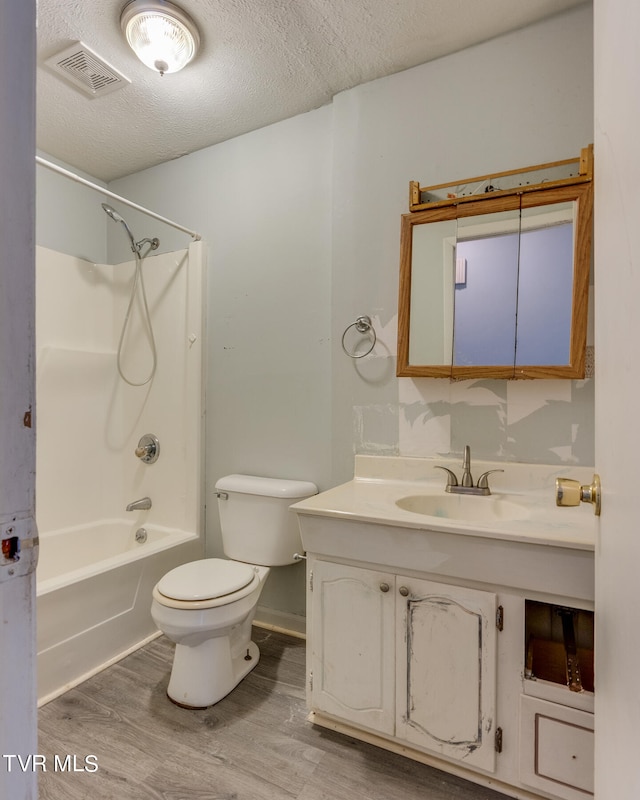 full bathroom with vanity, wood-type flooring, a textured ceiling, shower / tub combination, and toilet