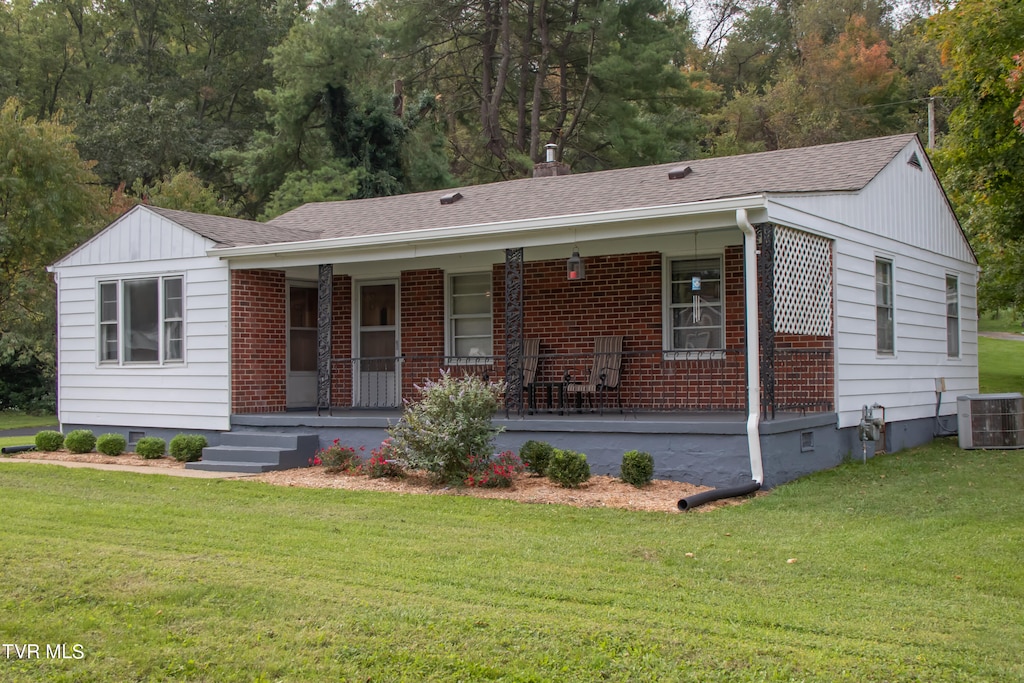 ranch-style house with cooling unit, covered porch, and a front yard