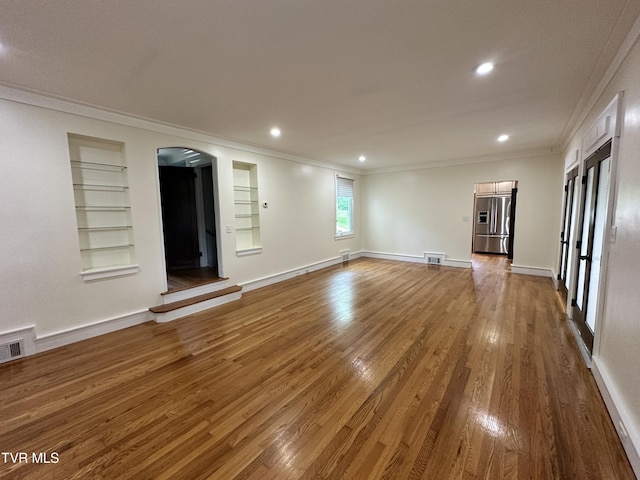 1357 Watauga St, Kingsport, TN 37660 - empty room featuring crown molding, built in features, arched walkways, wood finished floors, and recessed lighting
