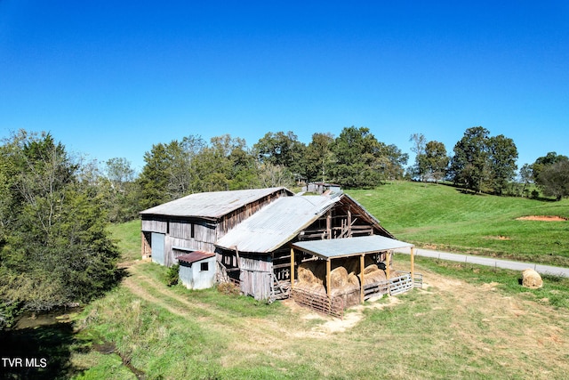 rear view of house featuring an outdoor structure and a rural view