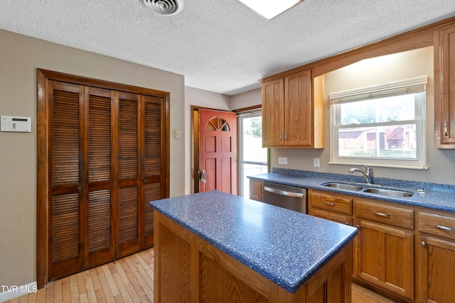 kitchen with a healthy amount of sunlight, a kitchen island, light hardwood / wood-style flooring, sink, and dishwasher