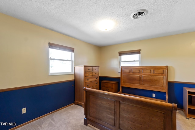 bedroom with light carpet and a textured ceiling