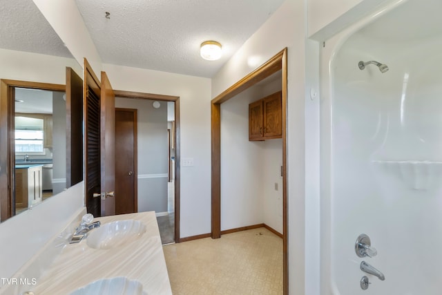 bathroom featuring bathtub / shower combination, vanity, and a textured ceiling