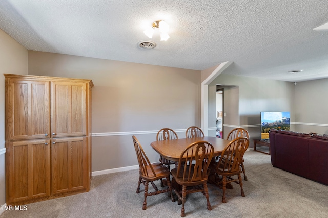 dining space featuring light colored carpet and a textured ceiling