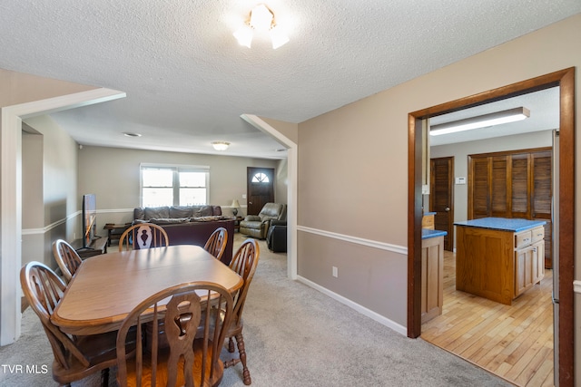 dining area with a textured ceiling and light wood-type flooring