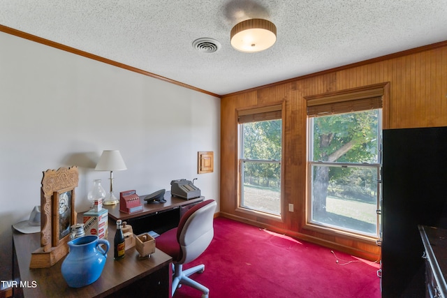 carpeted home office with wood walls, crown molding, and a textured ceiling