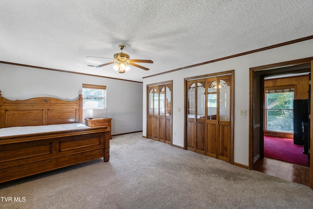 unfurnished bedroom with ceiling fan, light colored carpet, two closets, and multiple windows