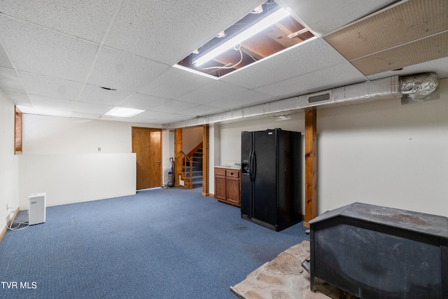 basement with a paneled ceiling, black fridge with ice dispenser, and carpet