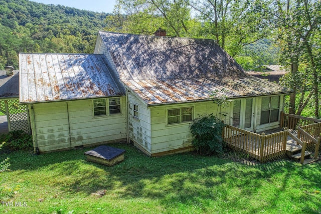 back of house with a deck and a lawn