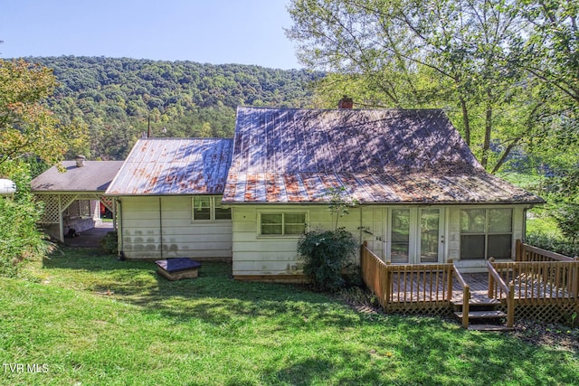 back of property featuring a wooden deck and a yard