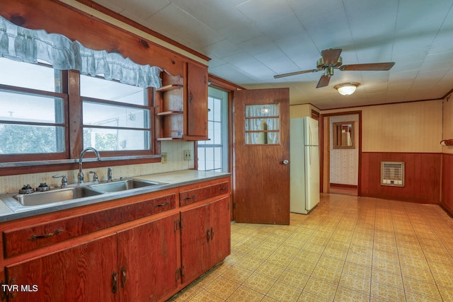 kitchen with plenty of natural light, wood walls, sink, and white fridge