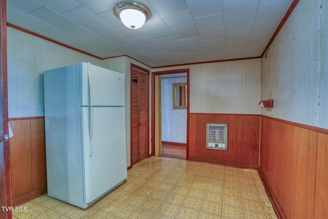 kitchen featuring ornamental molding, heating unit, white refrigerator, and wooden walls