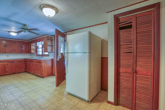 kitchen featuring ornamental molding, sink, ceiling fan, and white refrigerator