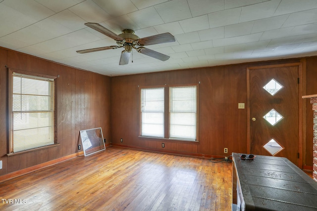 foyer featuring wood-type flooring, wooden walls, and ceiling fan