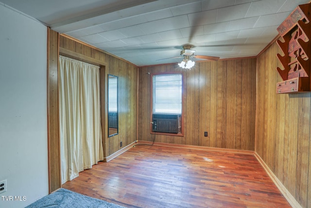 empty room with ceiling fan, hardwood / wood-style flooring, and wooden walls