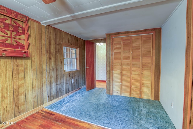 unfurnished bedroom featuring wood-type flooring and wooden walls