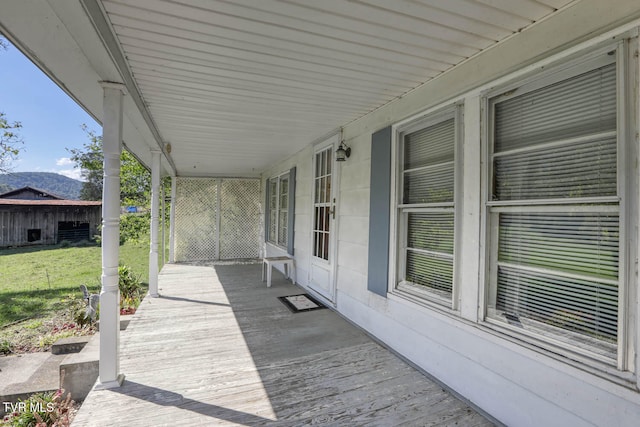 wooden deck featuring covered porch and a yard