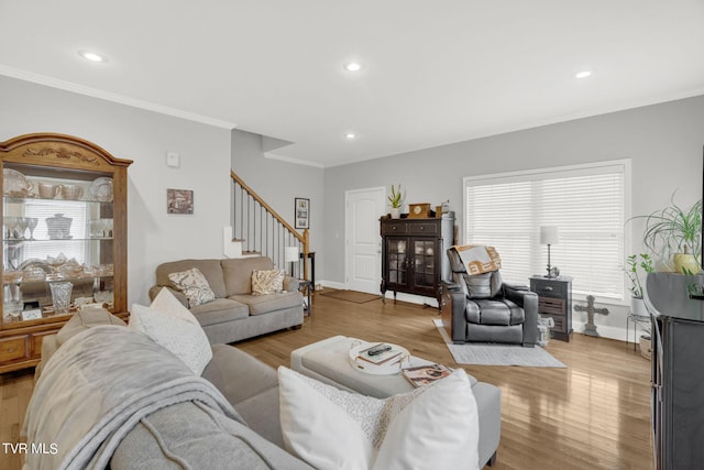 living area with light wood-style floors, ornamental molding, stairway, and baseboards