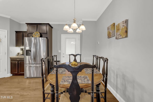 dining space with light wood-style floors, baseboards, ornamental molding, and a chandelier