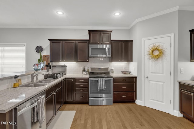 kitchen with light wood-style flooring, appliances with stainless steel finishes, decorative backsplash, and a sink